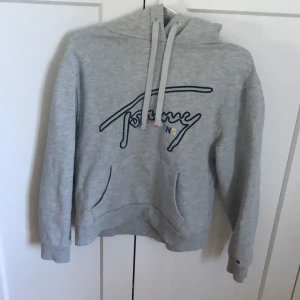 Hoodie från Tommy jeans storlek M - Såå skön och snygg grå Hoodie från Tommy jeans, storlek M men ganska kort i ärmarna. Använd 10 gånger! 