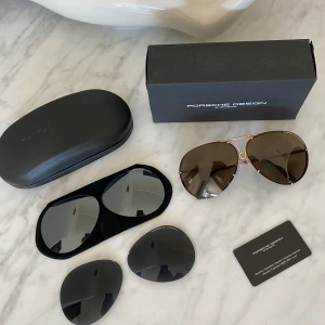 Porsche Design P8478 solglasögon - Säljer mina Porsche Design solglasögon i modellen P8478. Storlek 66. Guldiga bågar med bruna och spegelblå glas. Inklusive svarta glas som jag köpt till. Sparsamt använda, i väldigt bra skick. Nypris är 3800kr (+650kr för extra glasen). Säljes för 2200kr inkl frakt. Pris kan eventuellt diskuteras vid snabb affär. Skickas spårbart!