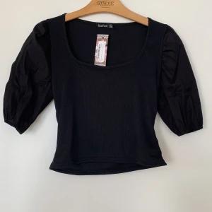 Topp med puffärmar - Oandvänd topp med puffärmar med prislappen kvar. Riktigt snygg urringning som passar till allt! 