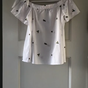 Söt sommarblus - En fin sommarblus med broderade kaktusar, of the shoulder med små knyten på axlarna, närmare 36 än 38 i storlek. Frakt ingår ej i pris.