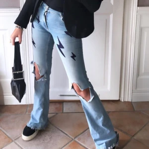 Bootcut jeans med blixtrar  - Blå bootcut jeans med hål och blixtrar! Skitsnygg och säljes billigt pga ett hål på en bakfickan (som lätt kan sys igen!) hålet visar inte rumpan hihi utan är bara på själva tyget på fickan