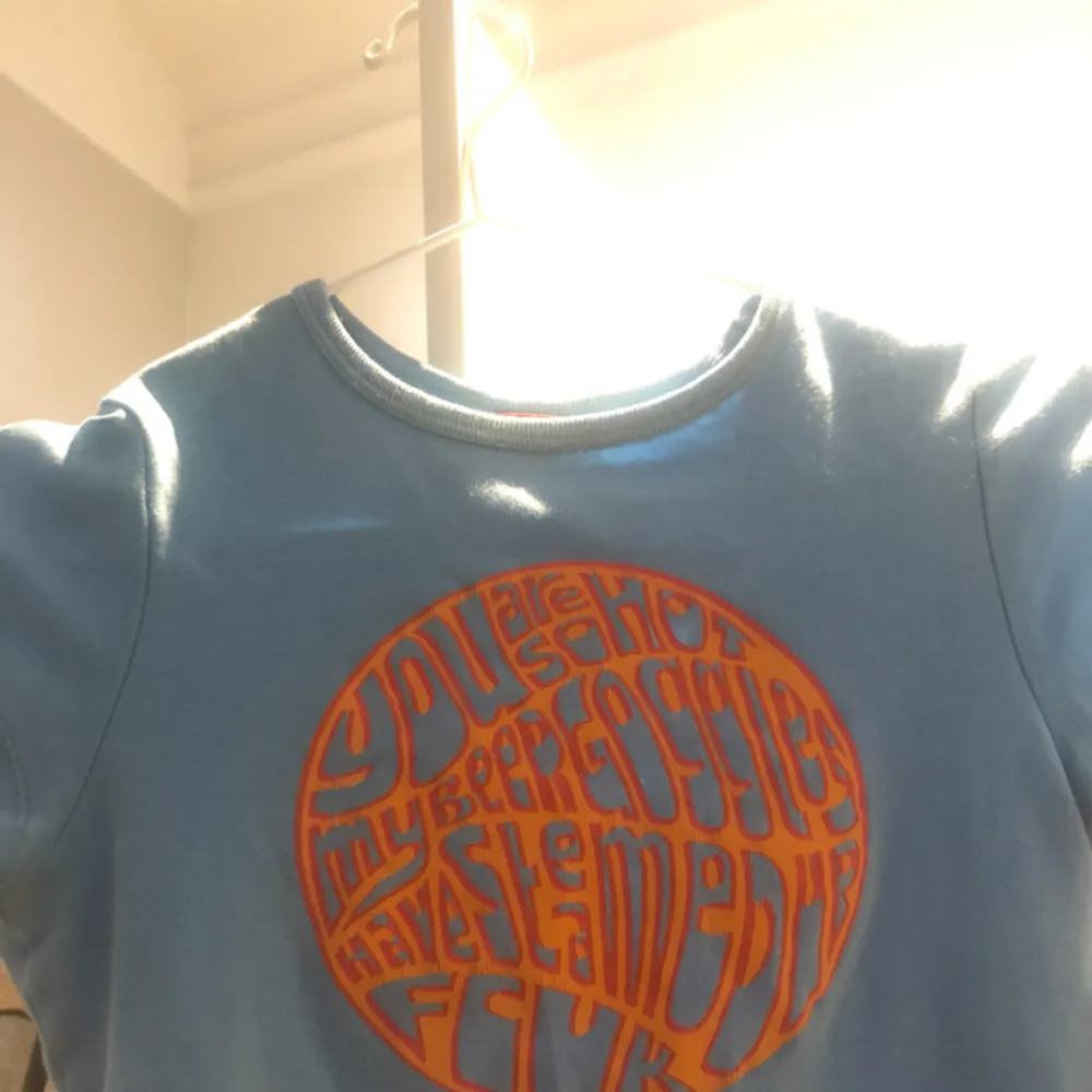 blå 70-tals t-shirt med oranget tryck, knappt använd:-) superfin nu till vår/sommar! frakten kostar 30 kr. T-shirts.