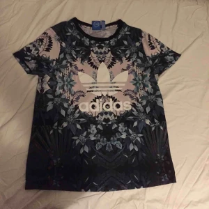  - ADIDAS-tshirt med asnajs blommigt tryck.  100%polyester 100%snygg