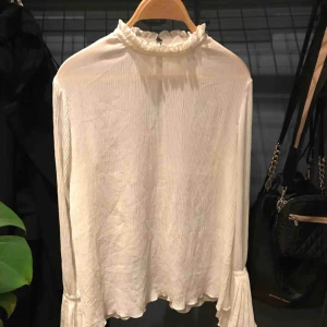  - Fin blus i tunt chiffong material från HM, storlek S. Blusen har en volang vid kragen och trumpetärmar. Knäppning i nacken. 