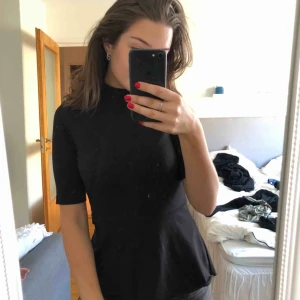  - Svart peplumtröja med en liten polokrage. Använd endast 1 gång. Köparen står för frakten.