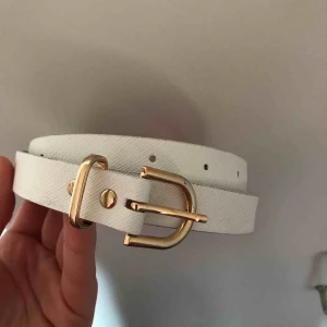  - Vitt skärp med gulddetaljer. 