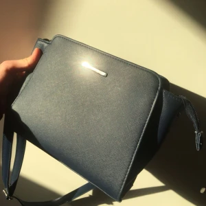  - En liten marin blå handväska. Använt bara en gång och ser helt ny ut. Metall detaljer på framsidan, sidorna och på banden. Justerbara band som kam bli väldigt långa. Ett stort fack som man får plats med mer än vad man tror i. Mötts i Stockholm eller skickar jag den till er, köparen står för frakt. ✨
