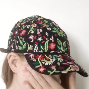  - Fin keps med broderade blommor.