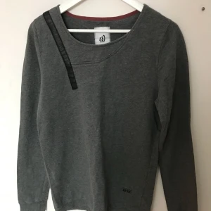  - ganska urringad mörkgrå tröja med detaljer i fakeskinn/ läder. köpt på junkyard för några år sen men sparsamt använd, inga skador. passar både tjejer och killar ✨  kom med bud, paketpriser vid köp av flera plagg. köparen betalar frakt