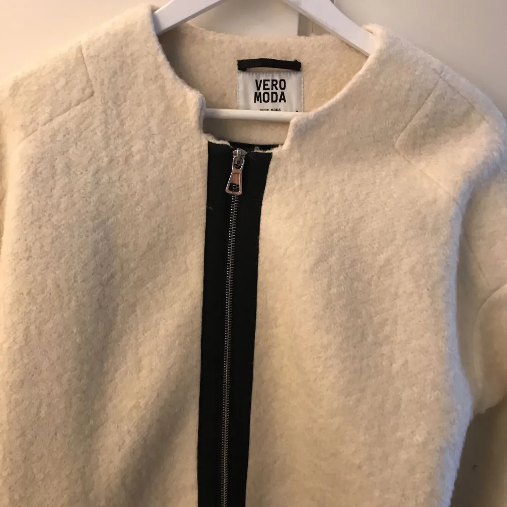 Ruggad kappa från Vero Moda i vitt med svarta detaljer, materialen är 50% ull och 50% polyester.   Frakt tillkommer om den ska skickas. . Jackor.