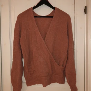 Stickad tröja  - Aprikos färjad tröja, färgen görs ej rättvisa på bilden, från NAKD. Kan användas åt båda hållen med överlappningen fram eller bak. Jättefin!!! 