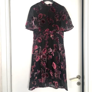 Klänning  - Superfin blommig klänning med fjärilsärm 🌺🌹🌸💃🏽. Blommorna är i sammetsaktigt tyg. Har dragkedja baktil och knyts i halsen så ryggen syns lite (se bild 3). Köptes på Cubus för 399 och aldrig använd. Ställ gärna frågor ✨