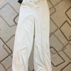 NLY TREND belt crepe straight pants vita - Vita byxor i mjukt material, mycket stretchiga. Resår i midjan som gör att de sitter bra. Aldrig använda.