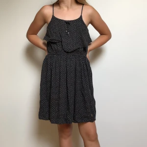 Mörk blå klänning med vit triangel tryck - Fladdrar vi bröstet och har en liten rosett uppe vid halsen. Slutar vid knäna och funkar toppen på sommarn!