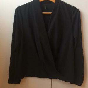  - Svart omlottop i tunt tyg, urringad och sjukt snygg! Använd endast tre gånger och i nyskick. Från United Colours of Benetton 