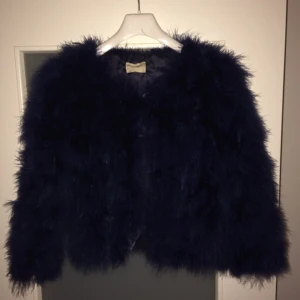  - Mörkblå fjäderjacka från WOS, gjord av ekologiska strutsfjädrar (fjädrarna är alltså tagna från strutsar som redan dött). Köpt på WOS-butiken på Hornsgatan för ca. 1 år sen för 1600. 