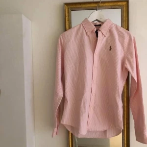 Ralph Lauren slim fit skjorta strl 4 - Vad: Ralph Lauren skjorta, i slim fot modell.  Storlek: 4 (US) Material: 100 % bomull  Skick: Använd ett fåtal gånger. Efter noggrann granskning under lampa kunde jag ana små skiftningar i armhålan från deo (inget jag såg i dagsljus), se närbild fotat under lampa. (ordinarie pris 1095 kr).