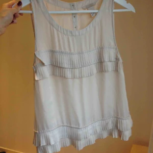  - Topp med fina plisseringar och guldknappar i nacken. Passar på fest eller under kavaj på jobbet. Bra skick.