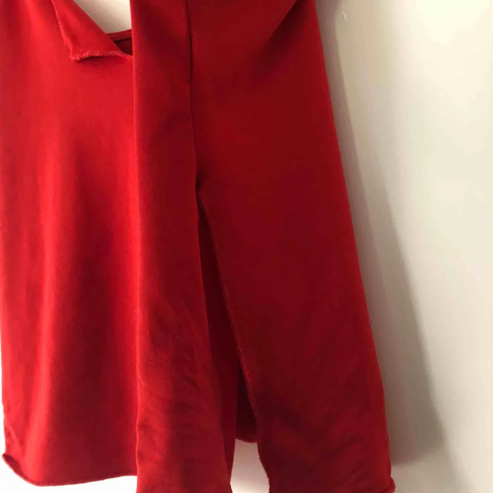 Rött linne med slitsar på sidorna och vid brösten. Stretchigt material. . Toppar.