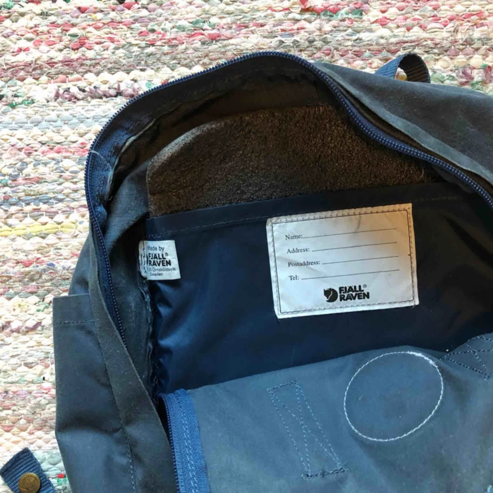 Traditionell blå Kånken ryggsäck i ”original” storlek. Köpt för ca 5 år sedan men inte använd på flera år. I gott skick, med några slitningar undertill.   Sittunderlag ingår. Säljes pga av garderobsrensning!. Väskor.