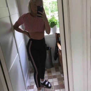  - Högmidjade svarta jeans med röda sträck längs sidorna. Högmidjade och i bra skick. Fraktas emot fraktkostnad, byts eller möts upp!