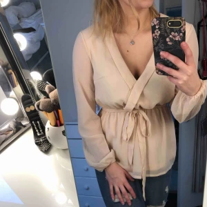  - Jättefin beige/ljusrosa blus från NLY Trend i storlek 36 (S). Praktiskt taget nyskick då jag enbart använt den en gång. V-ringad med resår och snörning i midjan.  Köparen står för frakt 🌸