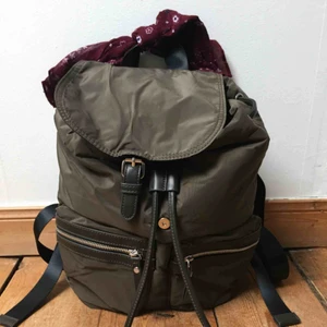 Ryggsäck med scarf - Ny ryggsäck som ej använts. Dragsko upptill med knäppning på locket. Smidiga fickor fram. Scarfen medföljer och går att ta bort.