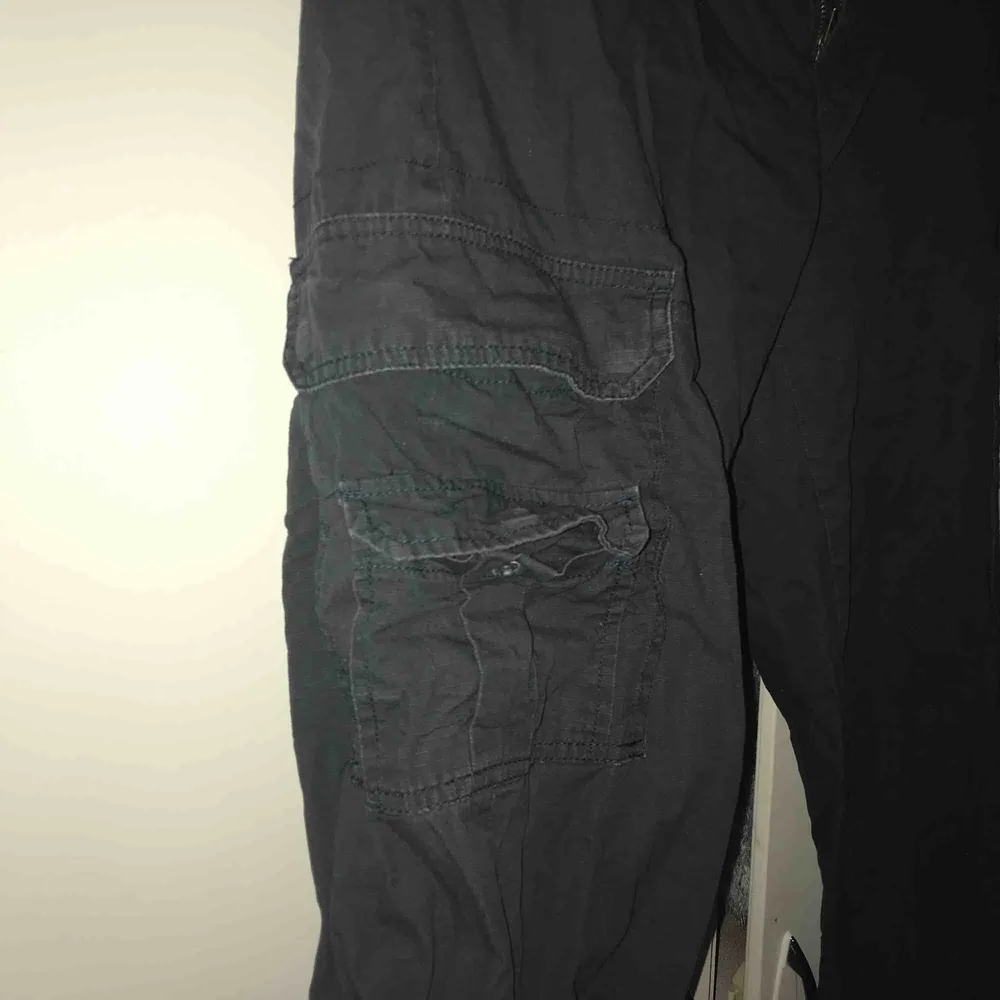 Black cargo pants, köpta här på Plick och insydda så de sitter ordentligt i midian. Går att spänna vid anklarna  Skick:använda i gott skick. Jeans & Byxor.