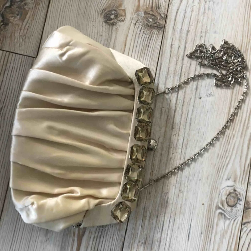En ganska liten väska som har fina ”stenar” på framsidan och har en liten ficka inuti. . Väskor.