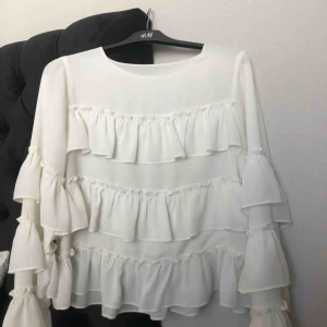  - Vit långärmad med volanger, nästan helt oanvänd.
