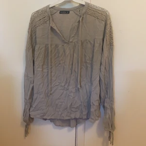 Beige/grå blus - Säljer en beige/grå blus ifrån Ruth and circle. Strl 38, 40kr. Fina spetsdetaljer över axlarna. Köparen står för frakt.