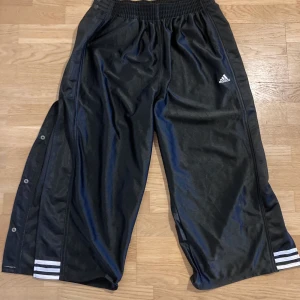 Retro Adidasbyxor med knäppning  - Dom här adidasbyxorna är så satans snygga‼️ Så fina detaljer med knäppning på sidorna och glansigt tyg, mkt bra skick! Dom är i str S men skulle snarare säga att dom är M! 🖤🤍🖤🤍🖤🤍🖤