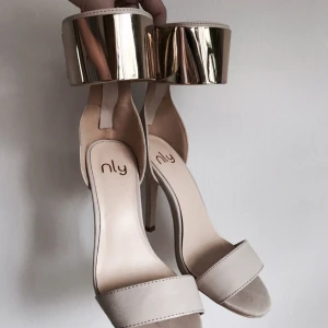  - Beiga klackar från Nelly med guldiga detaljer. Endast använda en gång. Storlek 36
