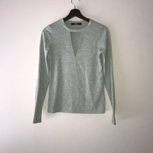  - Fin tröja i grå grön färg med en triangelformat urringning. Ett skönt tjock material i 78% polyester, 20% viskos och 2% elastan. Endast använd ett fåtal gånger. Notera: finns en liten foundation fläck från när tröjan köptes, fläcken syns knappt. Betalning sker via Swish och köparen står för frakten. 