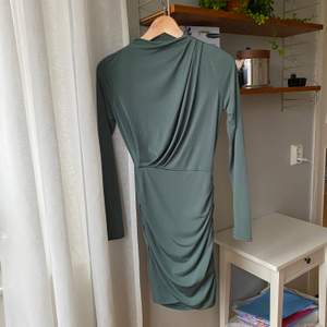 En snygg tajt klänning i fin olivgrön/grå färg. Den formar sig hur fint som helst efter kroppen och har en slits på ena sidan. ”Underkjol” är inbyggd så den är ej genomskinlig. Tyget är superstretchigt!