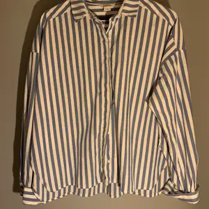 Oversized blå och vit randig skjorta från Monki stl M. Skjortan har vita knappar. Använd fåtal gånger, nyskick! Säljer skjortan för 100kr. 