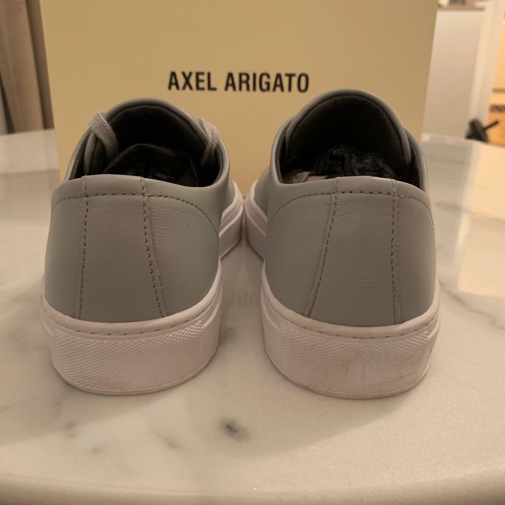 Ljusgrå sneakers från Axel Arigato med silverdetaljer längst fram. Storlek 37! Använda 1-2 ggr. . Skor.