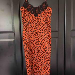 Skitsnygg silkesklänning i rostig-orange färg med svarta leopard-fläckar och svarta spetsdetaljer uppetill 🐆 midi-längd 