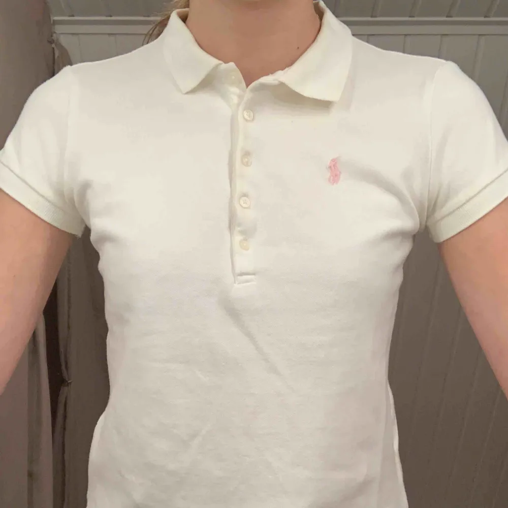 Vit piké med rosa detalj från Ralph Lauren, väl använd men bra skick. Köpt på NK i Stockholm, är en L i barnstorlek men passar som XS. T-shirts.