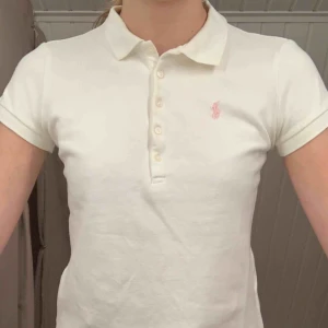  - Vit piké med rosa detalj från Ralph Lauren, väl använd men bra skick. Köpt på NK i Stockholm, är en L i barnstorlek men passar som XS