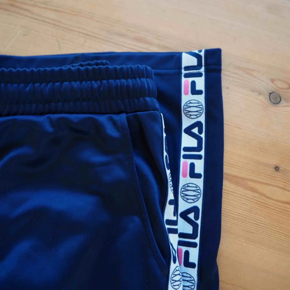 FILA trackpants ♥️❤️ Använda fåtal gånger.  Utsvängda i benen & har snöre i midjan för åtdragning.  Mörkblå färg med lite rosa på sidorna på detaljerna.  Frakt ingår! . Jeans & Byxor.