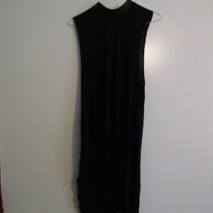  - Svart klänning med "fladdrande släp" i sidorna, går till knäna på den främre delen. liten dragkedja i nacken, fakeskinn i kragen. strl S/M, köpt på H&M.