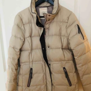  - Kort, figurnära dunjacka från Espirit. Köpt för ett par säsonger sedan. Avtagbar, fodrad huva, fästs med dragkedja mellan huva och jackan. Mycket skönt! Lång ärm med mudd. Khakibeige. 