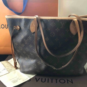  -  LV Neverfull MM haft inlämnad för byte av lädret runtom, det skinnet är ljusare just nu när det är nytt, men mörknar med tiden.axelbanden är mörkare o har gått upp lite i en söm. Dessa kan man byta ut på LV butiken.Kvitto dustbag o låda finns.   