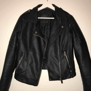  - En svart oanvänd jacka i fake skin. Super snygg och har används ca 1-2 gånger bara. Inte använt den för den är för liten. Normal i storlek! Snygga detaljer på axlarna! 