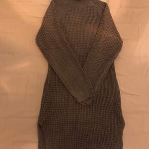 En lång mörkgrå stickad tröja med en liten slits i strl M. 