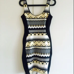  - Jättesnygg klänning med guldigt/vitt/svart tribalmönster. De svarta sidorna formar kroppen grymt bra. Extra innertyg vid bysten (men inte tillräckligt tjockt för att agera som BH). Använd ca 2-3 gånger så nästan helt ny! Har du frågor får du höra av dig 😊
