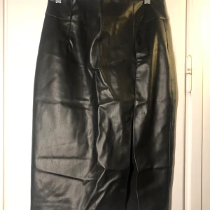 Läderimitation kjol - En slits fram till, går till knäna på mig som är 175cm lång