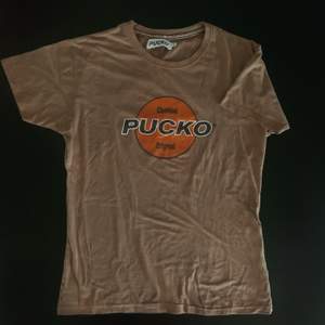 Asball t-shirt från PUCKO vintage i beige/brun nyans! Storleken passar en Medium om man vill att den ska sitta tight, för lösare passform skulle jag säga S/xs🍀 (läs min bio innan beställning)