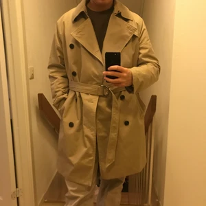 Beige Trench Coat - Snygg trench coat med snyggt ringspänne. Sitter snyggt på XS-M. 